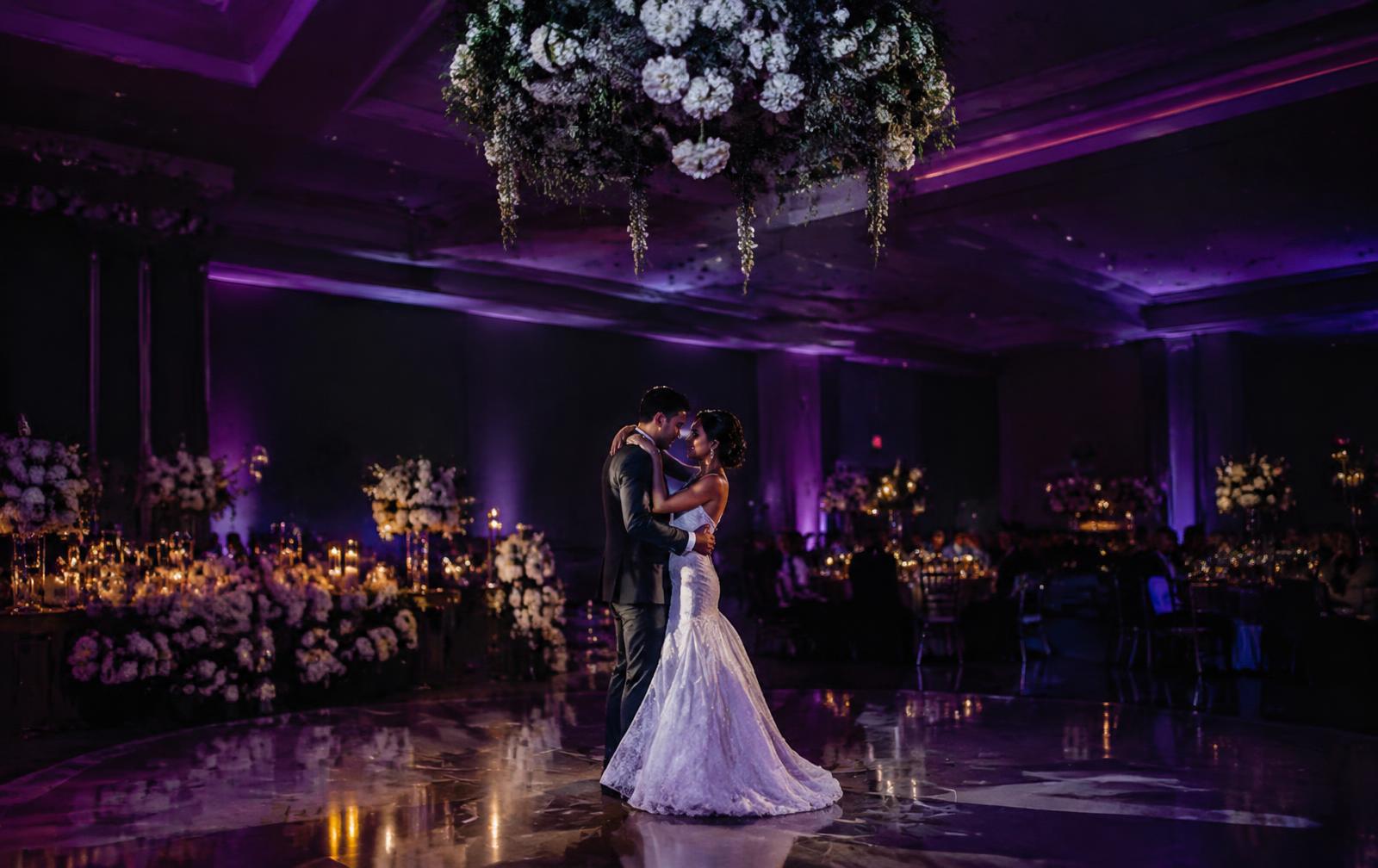 Couple's first dance on a purple-uplit dancefloor